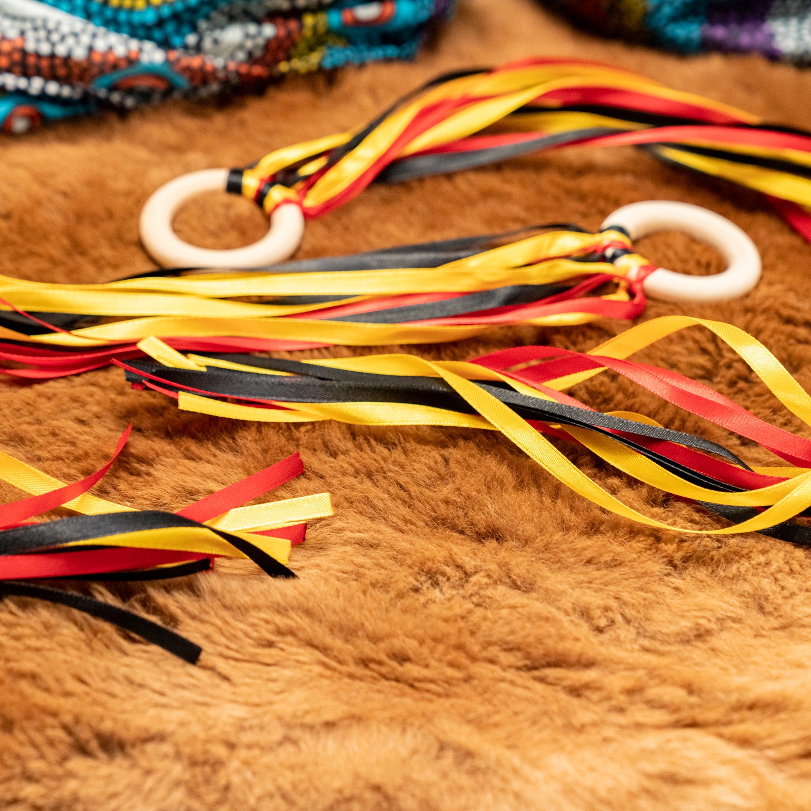 Two hand kites with Aboriginal inspired designs in black, yellow, and red colors, laid out on a furry surface.