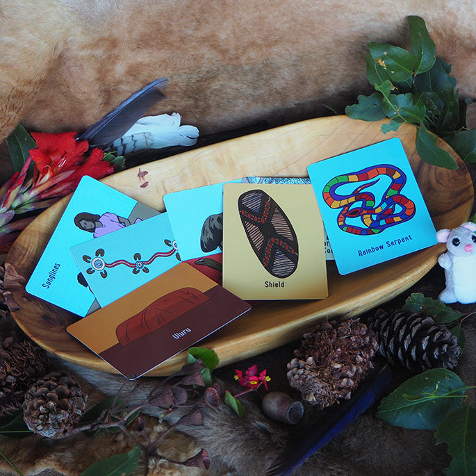 A collection of colorful topic cards about Aboriginal Australia displayed on a wooden surface with decorative items around.